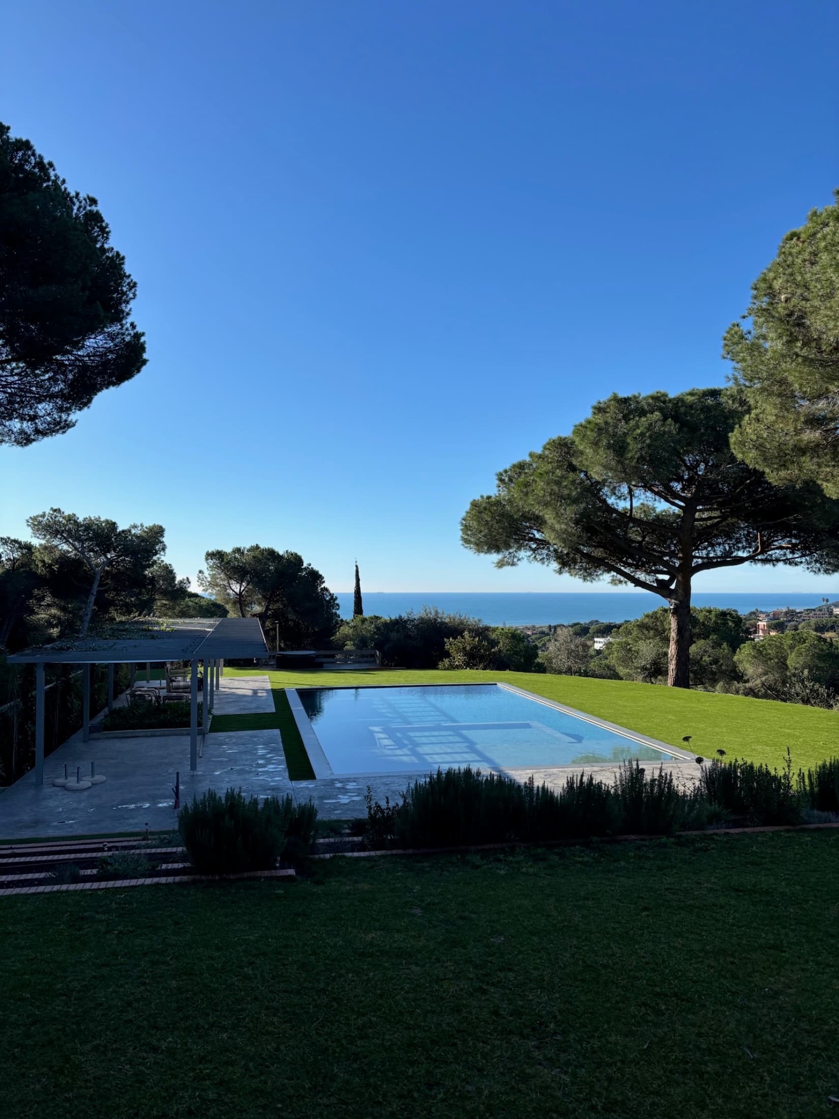 Jardín residencial con piscina y vista al mar